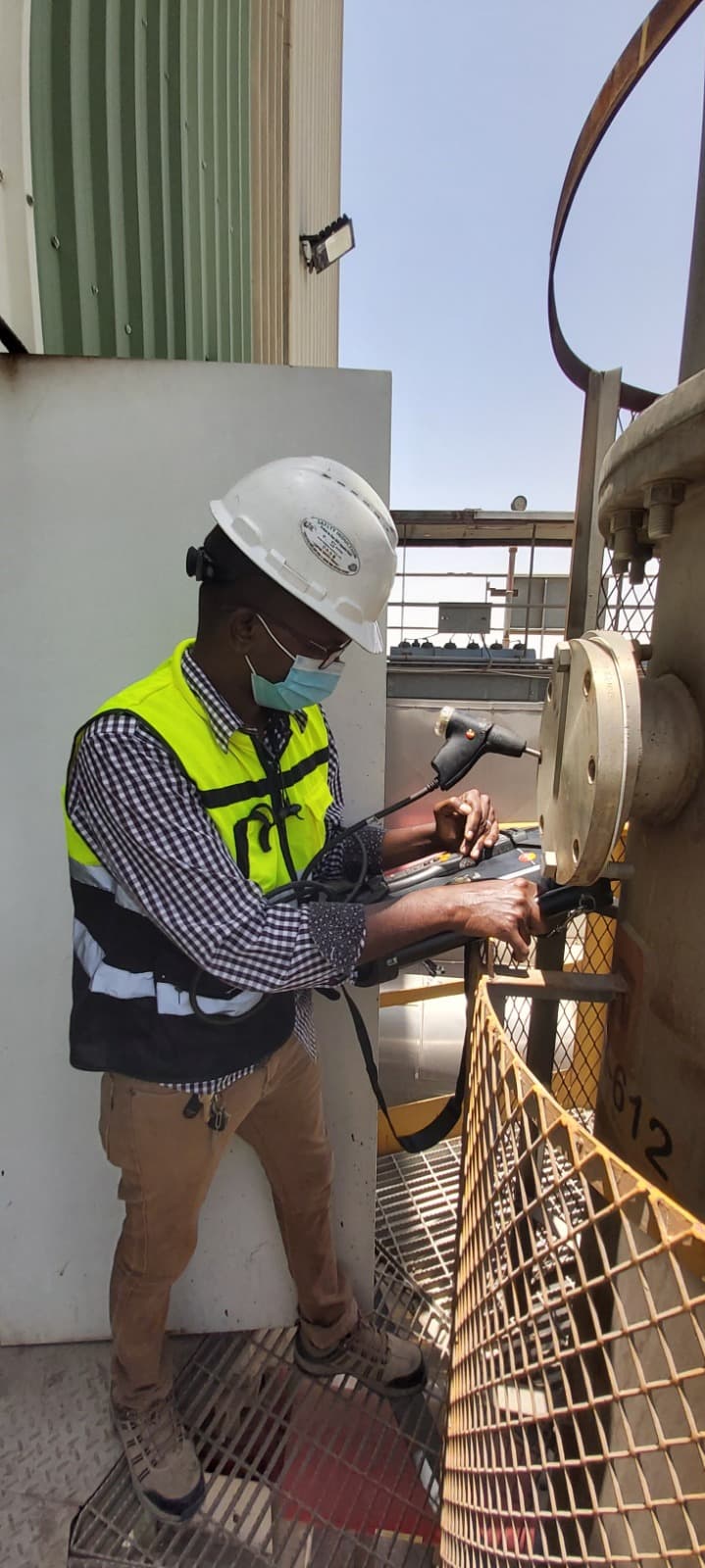 Technician using handheld gas analyzer at factory