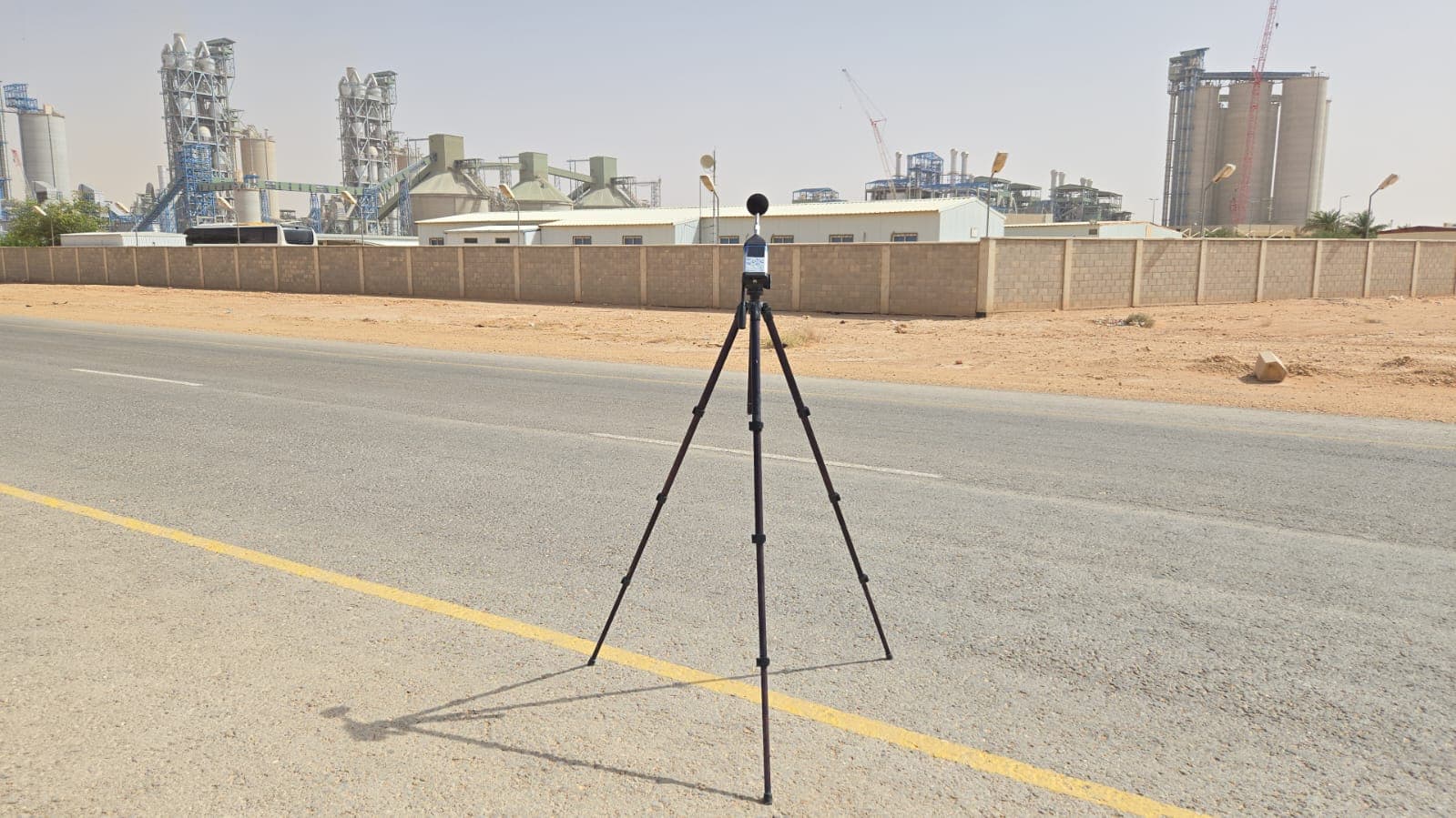 Sound level meter on tripod for noise monitoring at industrial cement facility