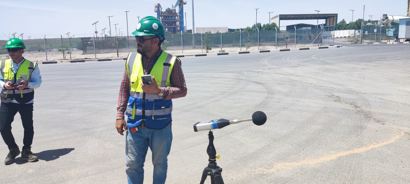 Field workers in safety gear conducting noise monitoring at industrial facility